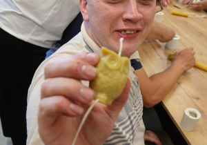 Mężczyzna trzyma w ręku świecę w kształcie sowy.