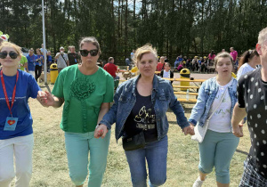 Grupa tańczących osób trzymających się za ręce.