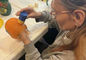 Kobieta wykonuje barwi na pomarańczowo słoik.