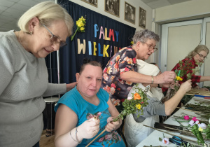 Kilka kobiet wykonuje palmy wielkanocne.